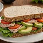 A beautifully plated Turkey Avocado Sandwich with layers of turkey, avocado, lettuce, and tomato.